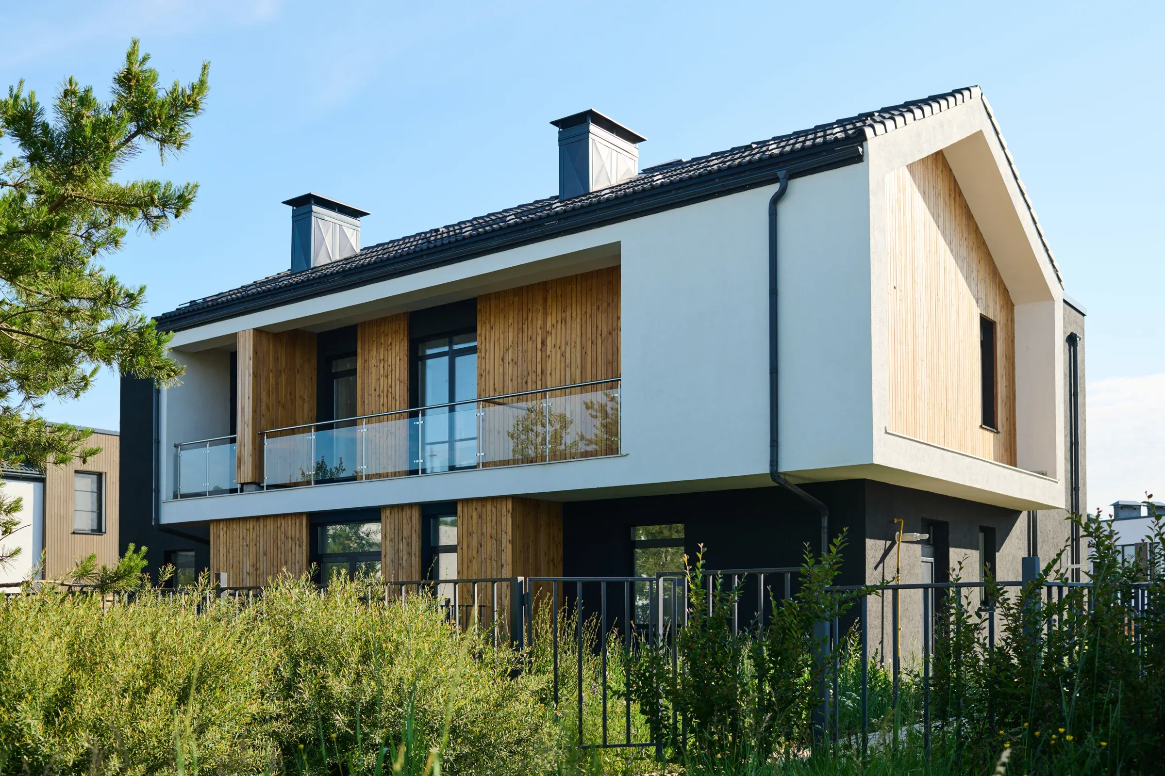 Modernes Wohnhaus mit heller Fassade und Holzelementen an einem sonnigen Tag