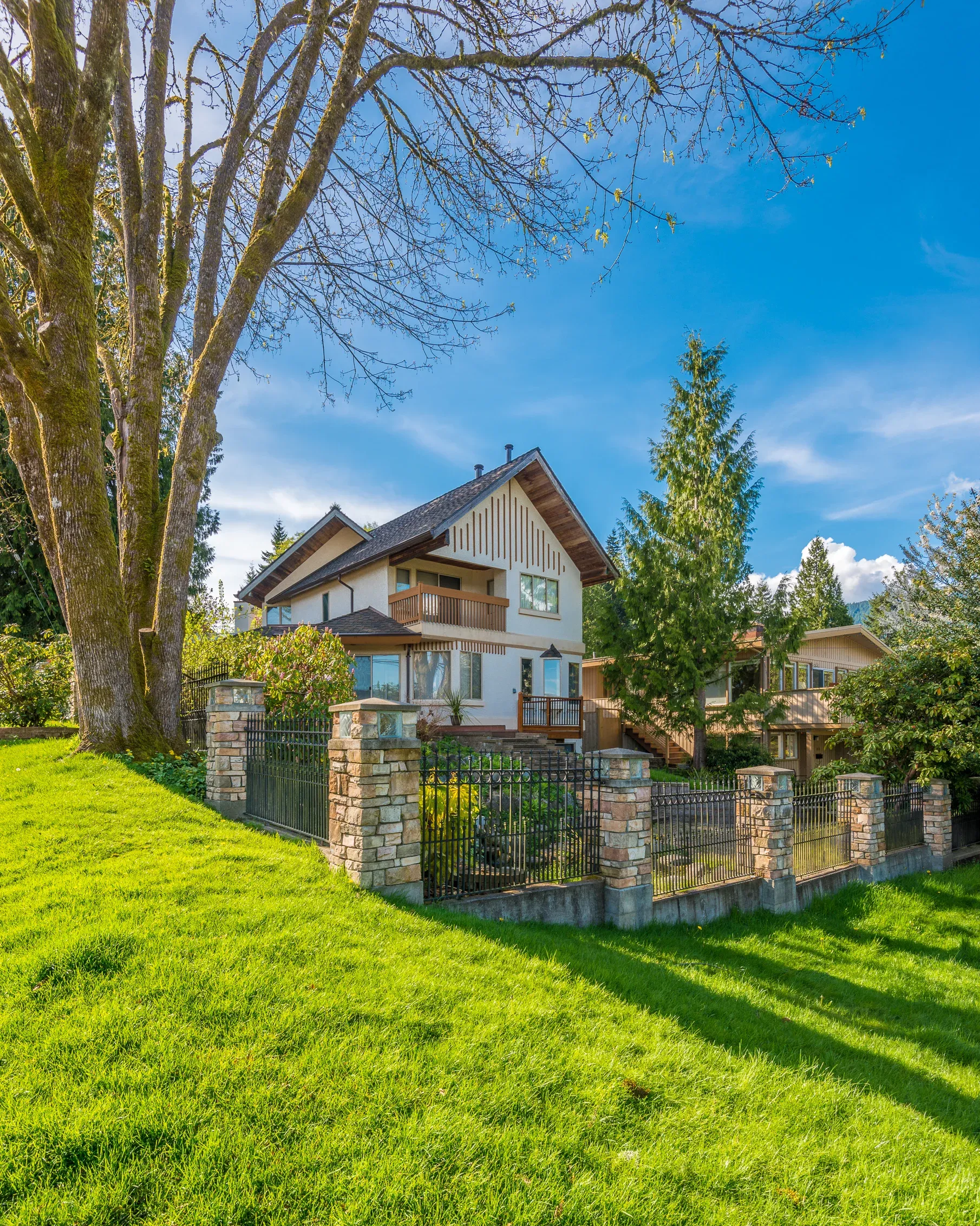 Einfamilienhaus mit Zaun aus Natursteinpfeilern und Metallfeldern im Grünen